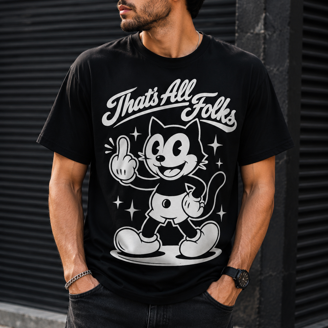A man wearing a black graphic t-shirt with a white retro cartoon cat design and the text 'That's All Folks'. He is wearing black sunglasses and dark jeans, standing in front of a dark gray corrugated metal wall.