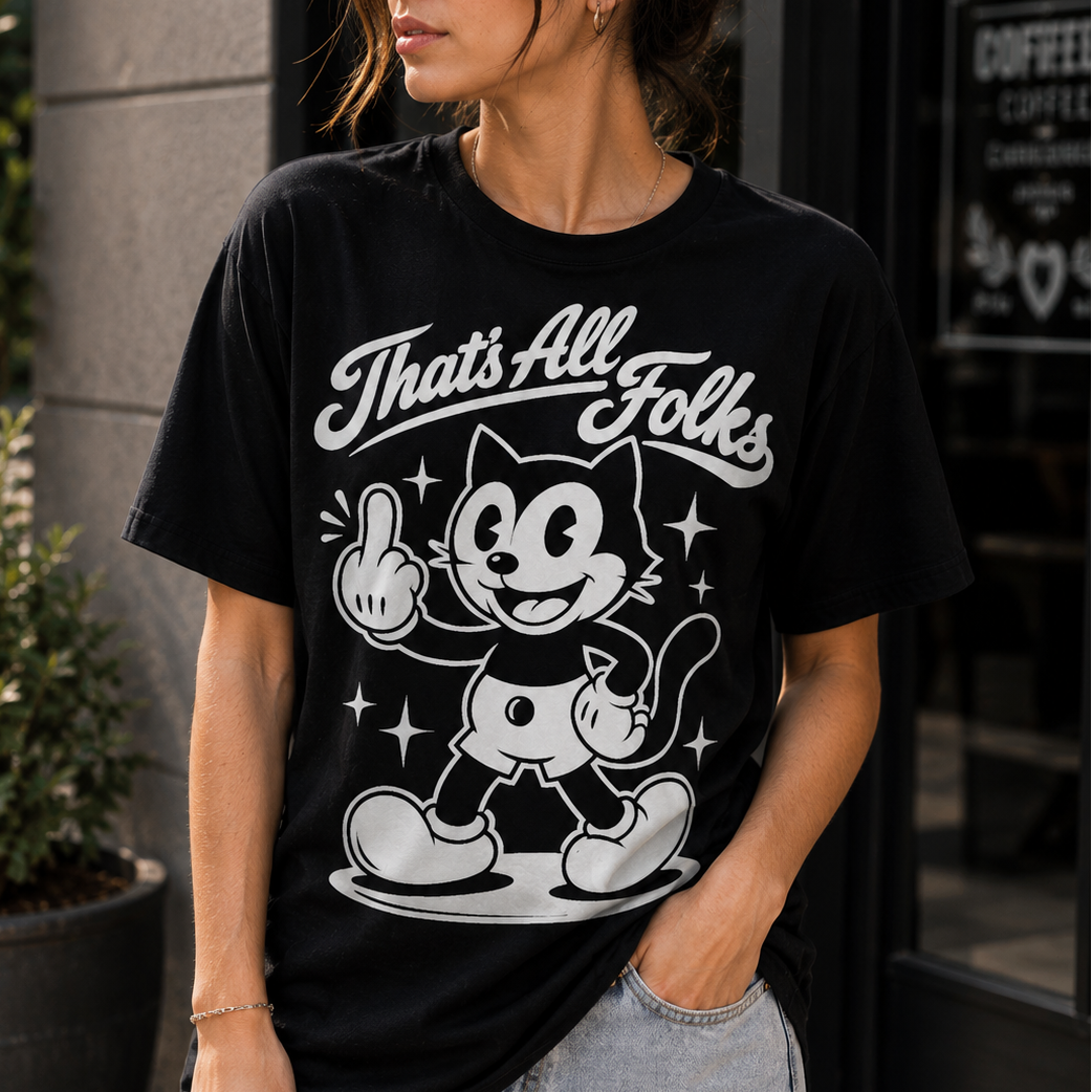 A woman wearing a black graphic t-shirt with a white retro cartoon cat and the text 'That's All Folks', paired with light-wash jeans, standing outdoors in front of a storefront.